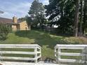 Spacious backyard showcasing mature trees, a grassy area, and a fenced perimeter at 1819 Collier Rd, Durham, NC 27707