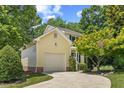 Lovely exterior of home featuring yellow siding, an attached garage, and mature landscaping at 20 Nicklaus Way, Clayton, NC 27520