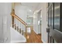 Bright foyer featuring hardwood floors, staircase with wooden railing, and views into the living spaces at 2069 White Pond Ct, Apex, NC 27523