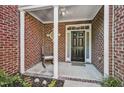 Inviting brick porch with white columns and a rocking chair, offering a cozy entrance to the home at 2069 White Pond Ct, Apex, NC 27523