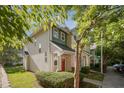 Townhome exterior featuring a red front door, verdant landscaping, and charming architectural details at 2261 Plum Frost Dr, Raleigh, NC 27603