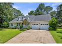 Traditional ranch home with dormer windows and attached two-car garage, surrounded by mature trees and a well-maintained lawn at 3109 Gold Dust Ln, Willow Springs, NC 27592