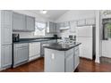 Bright kitchen featuring gray cabinets, stainless steel appliances, island and hardwood floors at 4505 Woodlawn Dr, Raleigh, NC 27616