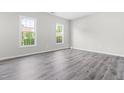 Bright bedroom features two windows for ample natural light, gray walls, and stylish laminate flooring at 5309 Neuse Wood Dr, Raleigh, NC 27616