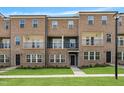 Three-story brick townhouse with individual balconies, a front entrance, and manicured lawn at 547 Forestville Rd, Wake Forest, NC 27587