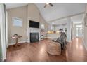 Inviting living room featuring hardwood floors, a fireplace, vaulted ceilings, and a seamless flow into the adjacent open kitchen at 80 Scarlet Bell Dr, Youngsville, NC 27596