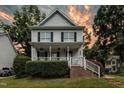 Charming two-story home boasts a welcoming front porch and manicured landscaping against a stunning colorful sunset at 8513 Buscot Ct, Raleigh, NC 27615