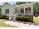 This home features a cozy front porch with white railings and attractive landscaping at 119 Percheron Dr, Zebulon, NC 27597