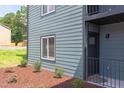 Close-up of an apartment building exterior with well-kept landscaping, showing the muted blue siding and black door at 1309 Hudson Ave # D6, Durham, NC 27705