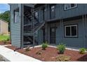 View of the apartment building showcasing exterior stairs, muted blue siding, and tasteful landscaping at 1309 Hudson Ave # D6, Durham, NC 27705