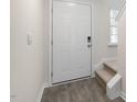 Bright entryway with gray wood-look floors, white door, and carpeted stairs at 150 Rusling Leaf Dr, Fuquay Varina, NC 27526
