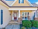 Inviting front porch with rocking chairs, stone pillars, manicured shrubs, and a stained wood front door at 1624 Struble Cir, Willow Springs, NC 27592