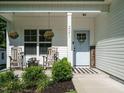 Cozy front porch seating area with hanging flower baskets, a 'welcome' sign, and a light blue front door at 221 Stella Way, Cameron, NC 28326