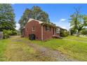 Exterior shot of a red brick home with a spacious yard, showcasing its classic design at 2512 Mckinney St, Burlington, NC 27217