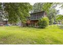 Backyard featuring a screened-in porch and wooden deck, surrounded by mature trees and a spacious lawn at 2712 Pebblebrook Dr, Sanford, NC 27330