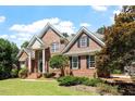 Charming two-story brick home with mature trees, lush green lawn, and inviting curb appeal at 312 Flint Point Ln, Holly Springs, NC 27540