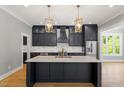 Modern kitchen with sleek, dark cabinets, quartz countertop island, and stainless-steel appliances at 3934 Old Chapel Hill Rd, Durham, NC 27707