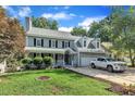 Traditional two-story home with a gray exterior, covered porch, manicured lawn, and attached garage at 4309 Birmingham Way, Raleigh, NC 27604