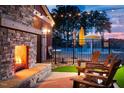Cozy outdoor patio with a stone fireplace, lounge chairs, and pool view at 48 Firefly Ln, Fuquay Varina, NC 27526