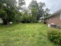 Spacious backyard with mature trees, grass lawn and rear view of brick home with HVAC units at 503 Adams St, Henderson, NC 27536