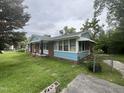 Brick house with blue trim featuring a screened porch and a fenced in yard on a cloudy day at 503 Adams St, Henderson, NC 27536