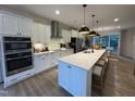 Modern kitchen features white cabinets, stainless steel appliances, and large island with pendant lighting at 5902 Dunzo Dr, Raleigh, NC 27617
