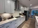 Modern kitchen featuring white cabinets, stainless steel appliances, a sleek cooktop, and stylish backsplash at 5904 Dunzo Dr, Raleigh, NC 27617