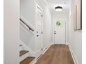 Bright hallway featuring wood floors, white walls, and a door with glass panels, leading to the home's entrance at 703 E Markham Ave, Durham, NC 27701