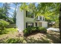 Well-maintained home with a lush green lawn, mature trees, and white siding with black shutters at 709 Woodgreen Dr, Durham, NC 27704
