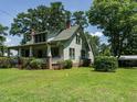 Landscaped lawn surrounds this charming house with a covered porch and mature trees at 714 Spring Ln, Sanford, NC 27330