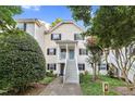 Inviting two-story condo with a light yellow exterior, black shutters, and landscaped front yard at 117 Scott Ln, Chapel Hill, NC 27514