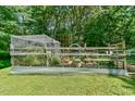Backyard garden with raised garden beds and a greenhouse, all surrounded by a wooden fence at 1205 Hillsborough Rd, Chapel Hill, NC 27516