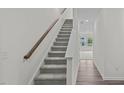 Carpeted staircase with wooden railing leading to the second level of the home at 1250 Pond Overlook Dr, Nashville, NC 27856