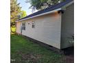 View of the house's side exterior showing the siding and a partial view of the backyard at 1512 E Lane St, Raleigh, NC 27610
