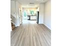Open-concept layout with sleek floors leading to the kitchen with stainless steel appliances at 189 Seville Way, Clayton, NC 27520