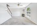 Well-lit living room with a fireplace, carpet flooring, a ceiling fan and a staircase nearby at 2101 Piney Brook Rd # 102, Raleigh, NC 27614