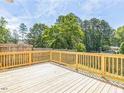 A wooden deck with railing overlooks the large, lush backyard at 2300 Radius Cir, Sanford, NC 27330