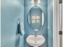 Cozy powder room with blue walls, white pedestal sink, an oval mirror, and nautical decor at 513 Woodson Dr, Clayton, NC 27527