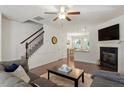 Bright living room with hardwood floors, a staircase, and a cozy fireplace with a TV mounted above at 7879 Allscott Way, Raleigh, NC 27612