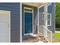 Close up of home's entrance with blue front door, brick steps, and decorative light fixture at 9508 Waterwood Ct, Raleigh, NC 27614