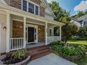 Inviting front porch with stone accents, brick steps, white railing and decorative plants at 1005 Fairfax Woods Dr, Apex, NC 27502