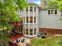 Back exterior view of the home showcasing a unique turret, spacious deck, patio, and well-maintained backyard at 105 Jolyn Pl, Chapel Hill, NC 27517