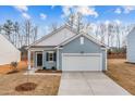 Single story home with blue siding, white trim and a two car garage on a sunny day at 1228 Pond Overlook Dr, Nashville, NC 27856
