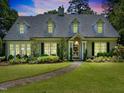 Inviting two-story home featuring dormer windows, a manicured lawn, and a stone pathway to the entrance at 1610 Ridge Rd, Raleigh, NC 27607