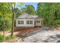 Exterior view of a charming home with white siding and dark shutters nestled among lush trees at 1952 Lewis Dr, Burlington, NC 27215
