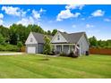 Well-maintained house with green lawn and complementary landscaping boasts covered front porch and attached garage at 282 Brodie Rose Landing Way, Smithfield, NC 27577