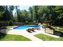In-ground pool with waterfall feature, surrounded by lounge chairs and a covered outdoor bar, perfect for summer gatherings at 308 Wescott Ridge Dr, Holly Springs, NC 27540
