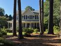 Two-story home with a welcoming front porch and classic blue shutters, viewed through a wooded landscape at 4117 Mangrove Dr, Raleigh, NC 27616