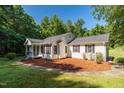 This single-story home features a charming porch, complemented by a stone pathway, lush lawn, and mature landscaping at 514 Lipscomb Grove Church Rd, Hillsborough, NC 27278