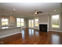 Open-concept living area with hardwood floors, fireplace, and large windows overlooking the backyard at 5491 Silk Hope Gum Springs Rd, Siler City, NC 27344
